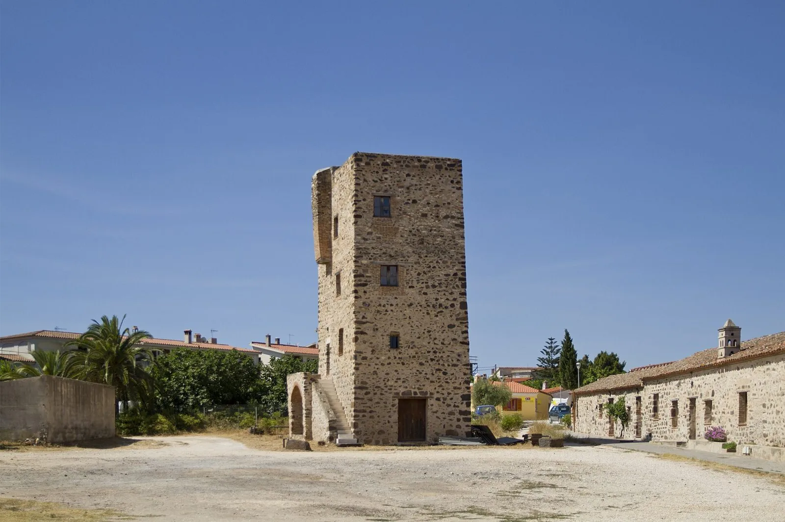 Torre medievale in pietra del complesso di Sant'Antonio Abate a Orosei, con le casette basse accanto